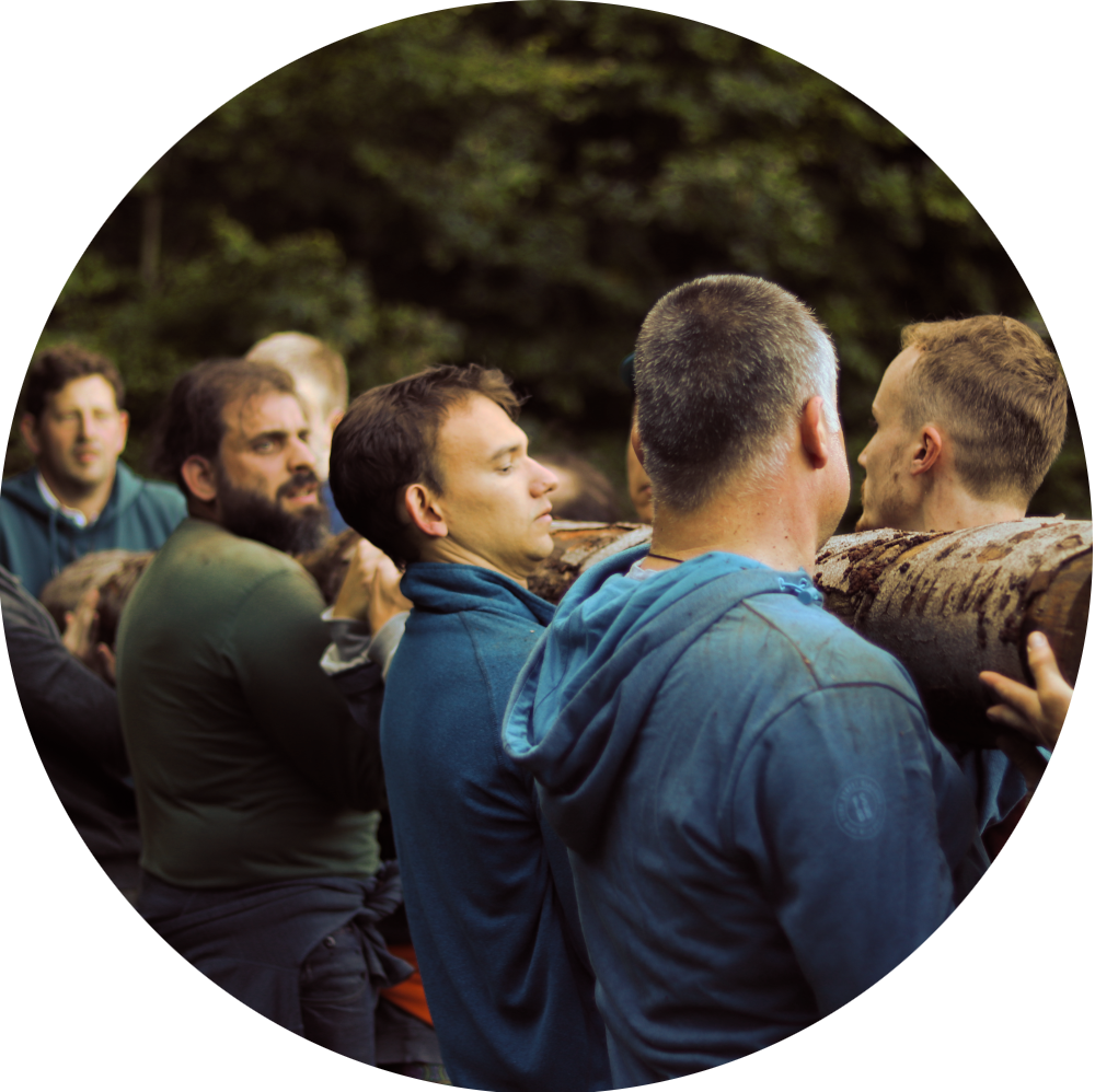 Tafelrunde-Stammtransport-Kreis-1K Männer tragen Baumstamm als Gruppen-Training